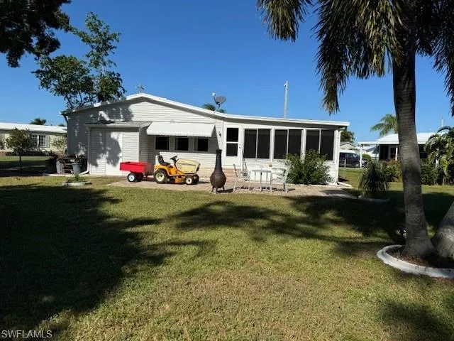 Back of property with a lawn and a sunroom