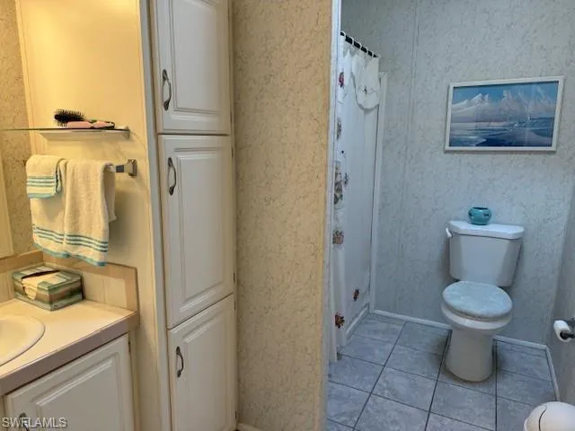 Bathroom featuring tile patterned floors, curtained shower, vanity, and toilet