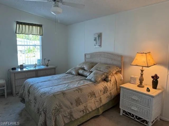 Bedroom featuring ceiling fan, carpet floors, and a textured ceiling