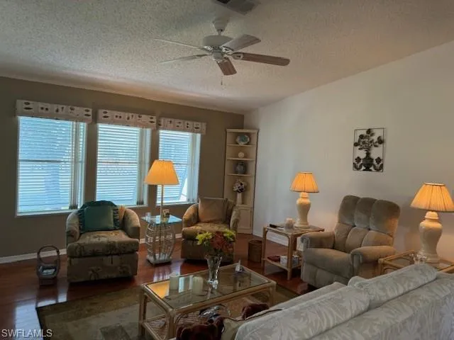 Living room with wood-type flooring, a textured ceiling, and ceiling fan