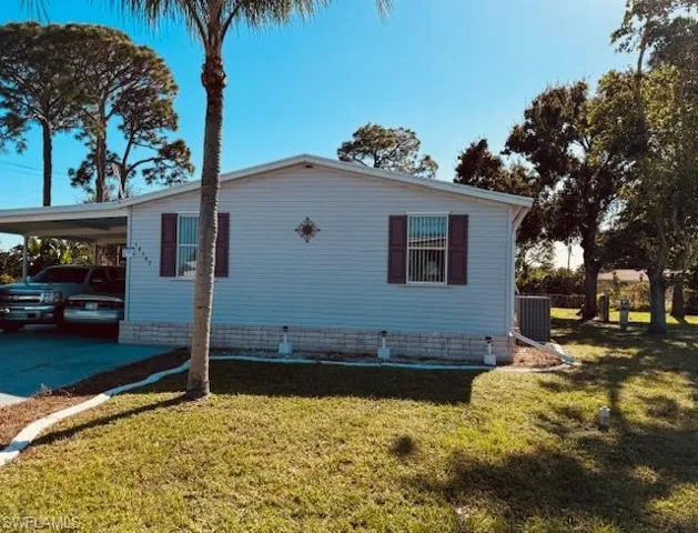 View of side of property featuring central AC, a yard, and a carport