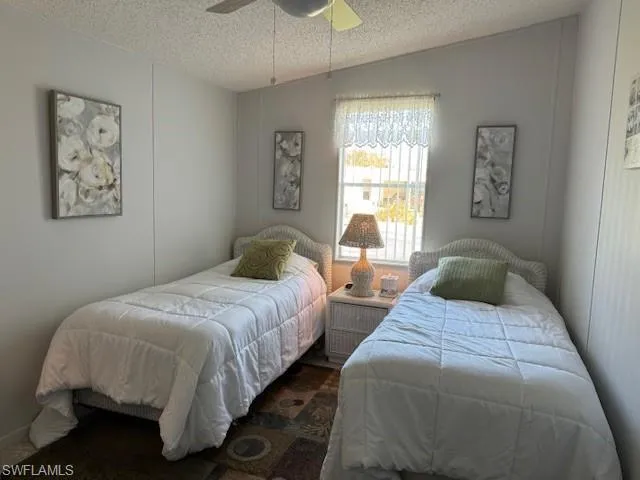 Bedroom featuring ceiling fan, lofted ceiling, and a textured ceiling