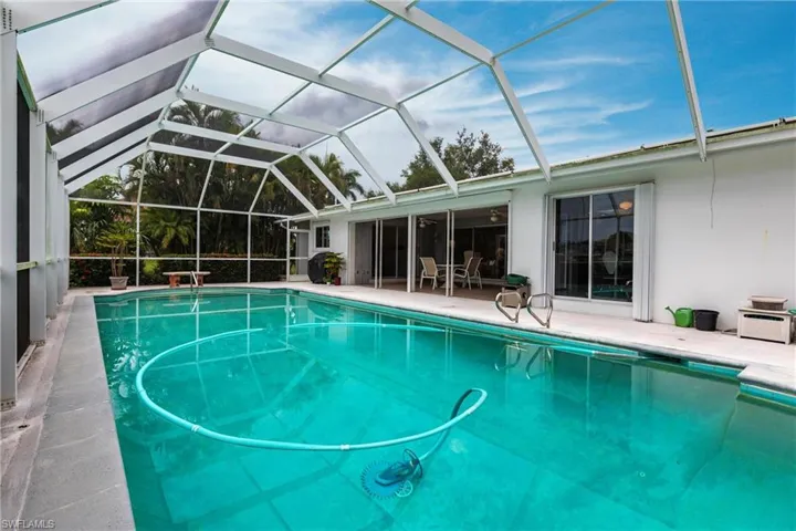 View of pool with glass enclosure and a patio area