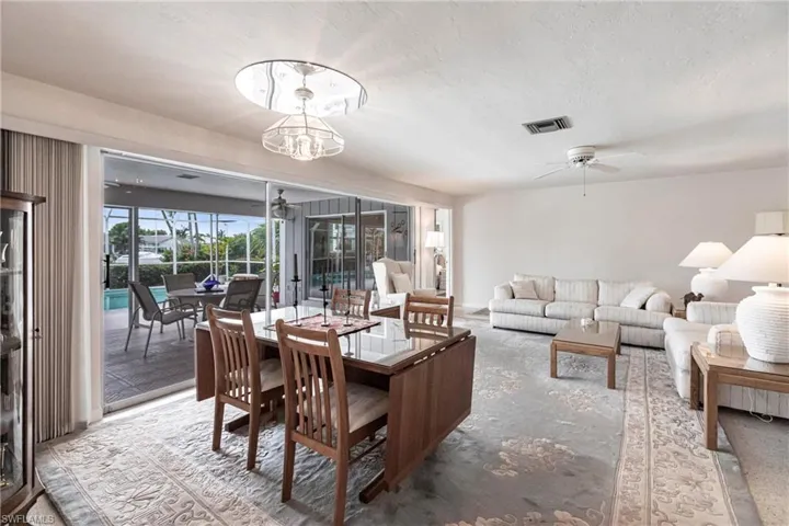 Dining room with a textured ceiling and ceiling fan with notable chandelier