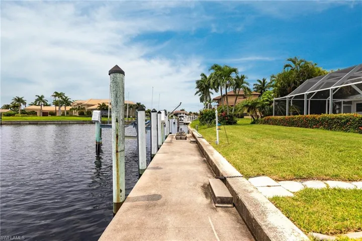 View of dock with a yard, a water view, and a lanai
