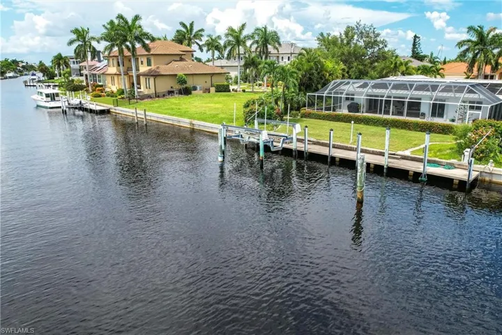View of dock featuring a water view, a yard, and a lanai