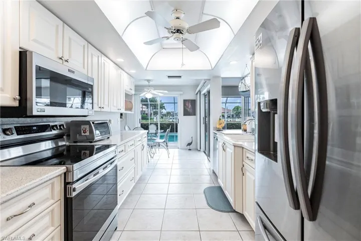 Kitchen with ceiling fan, white cabinets, sink, appliances with stainless steel finishes, and light tile patterned floors