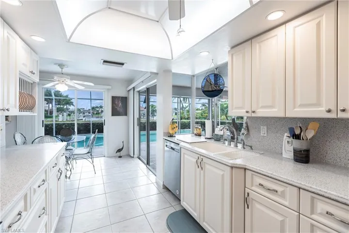 Kitchen with white cabinetry, backsplash, dishwasher, ceiling fan, and sink