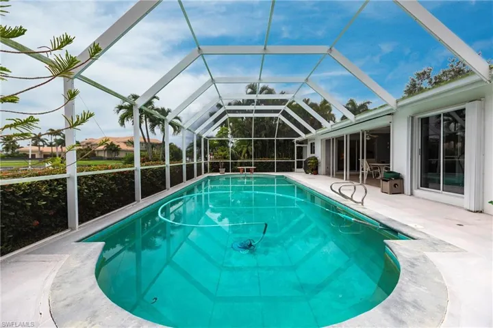 View of pool with a patio area and glass enclosure
