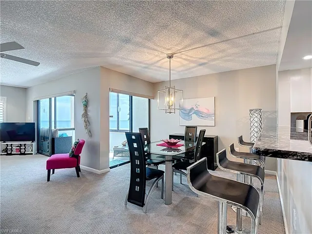 Living area featuring a textured ceiling, ceiling fan, and light colored carpet