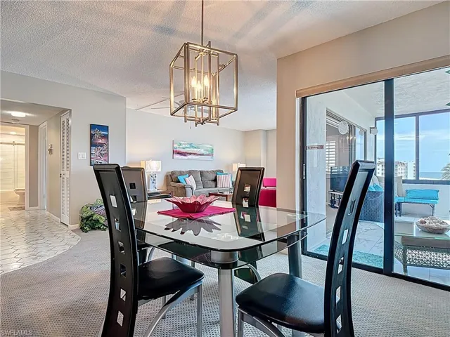 Dining area featuring a textured ceiling, carpet, a raised ceiling, recessed lighting, and a chandelier