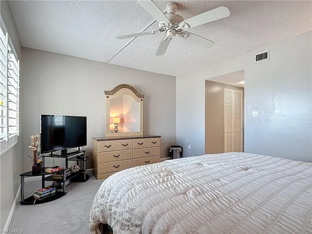 Bedroom featuring a textured ceiling, a ceiling fan, and carpet floors
