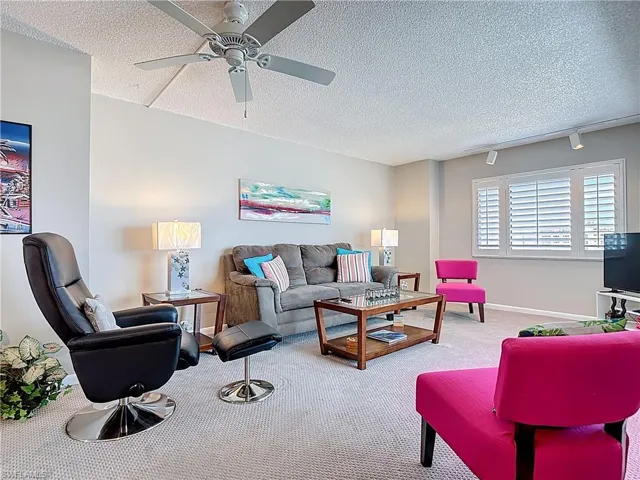 Kitchen featuring light colored carpet, ceiling fan, white cabinets, open floor plan, and a textured ceiling