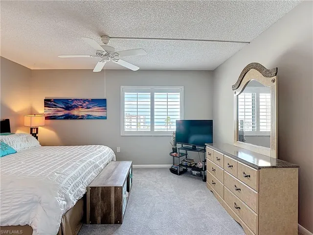 Carpeted bedroom featuring a textured ceiling and a ceiling fan
