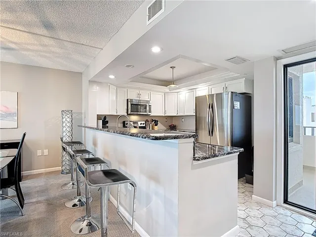 Dining room featuring a textured ceiling, carpet floors, and a chandelier
