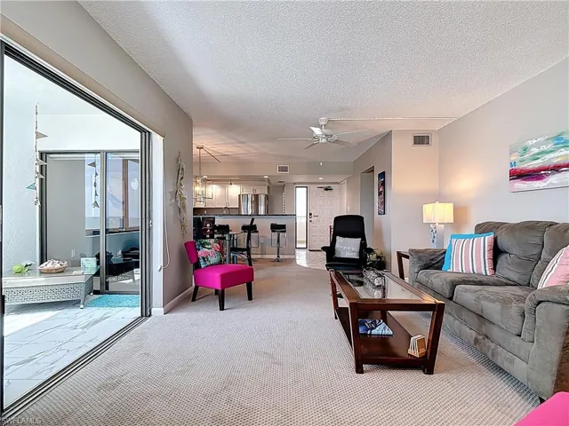 Sunroom featuring a textured ceiling, marble finish flooring, an outdoor living space, and carpet floors