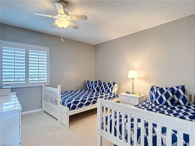 Bedroom with a textured ceiling, light carpet, and a ceiling fan