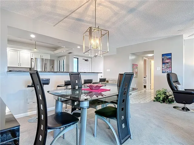 Living room with ceiling fan, a textured ceiling, and light colored carpet
