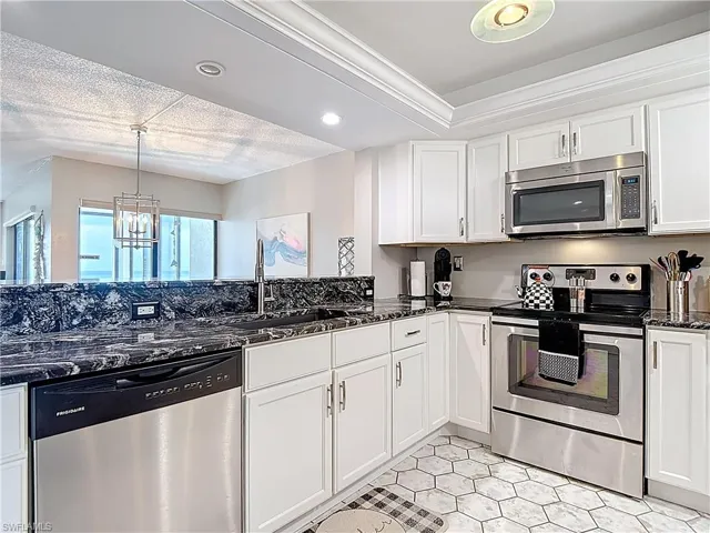 Dining space featuring a tray ceiling, a chandelier, a textured ceiling, light colored carpet, and recessed lighting