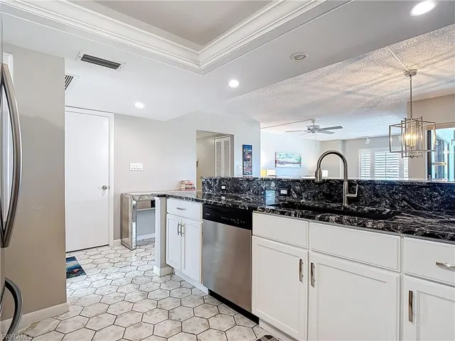 Kitchen featuring stainless steel appliances, dark stone counters, white cabinetry, recessed lighting, and a raised ceiling