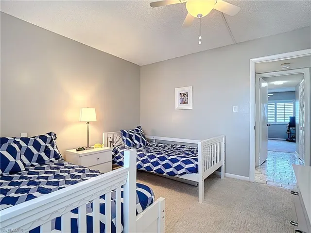Bedroom featuring a textured ceiling, light carpet, and ceiling fan