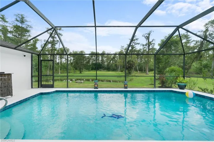 View of pool with enclosure and a back yard