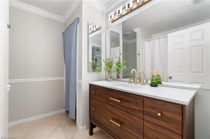 Bathroom featuring tile floors, vanity, and crown molding