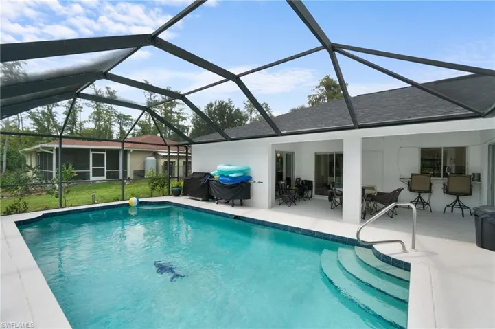 View of pool with enclosure, a patio area, and a yard