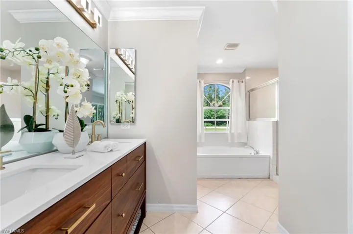 Bathroom featuring dual bowl vanity, tile patterned floors, crown molding, and plus walk in shower