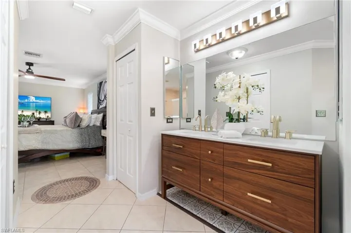 Bathroom with all tile floors, dual vanity, and crown molding