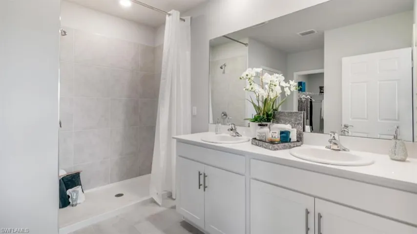 Bathroom featuring a shower with shower curtain and double sink vanity