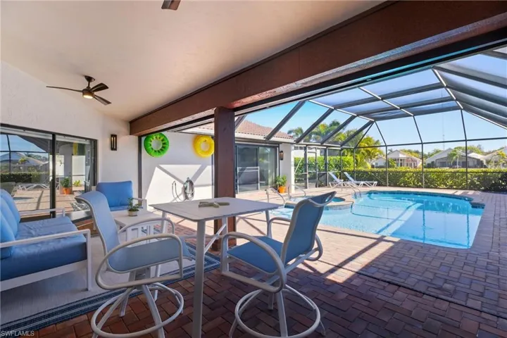 Outdoor pool featuring screen enclosure, a patio, a sunroom, a jacuzzi, and an outdoor living / dining area