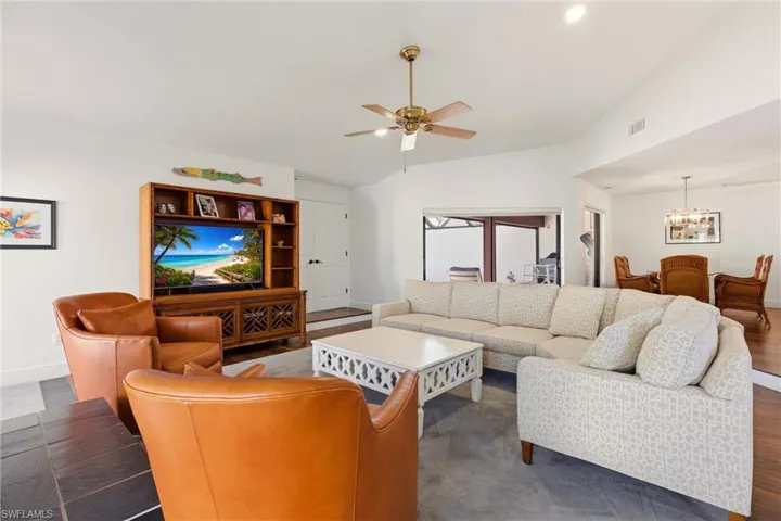 Living room with a ceiling fan, dark wood-style flooring, suspended lighting, and vaulted ceiling