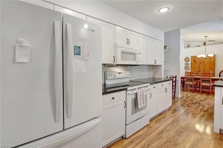 Kitchen featuring tasteful backsplash, light wood-type flooring, white cabinets, white appliances, and open shelves