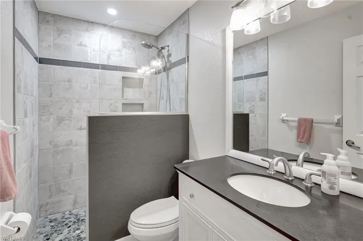 Full bathroom with a walk in shower, toilet, and vanity