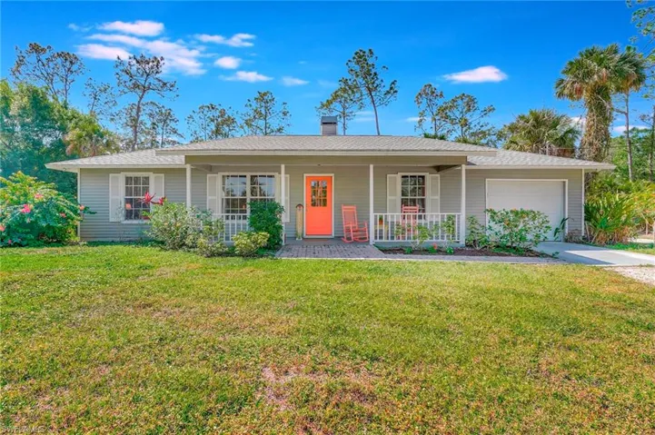 Ranch-style house with a porch, an attached garage, a chimney, concrete driveway, and a front lawn