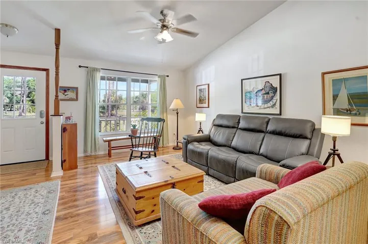 Living room featuring vaulted ceiling, a wealth of natural light, a ceiling fan, and light wood finished floors
