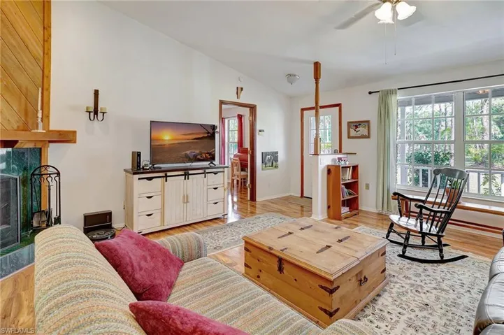 Living area with a wealth of natural light, light wood-style floors, a ceiling fan, and vaulted ceiling