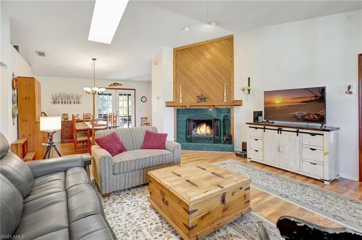 Living room with light wood-style flooring, vaulted ceiling with skylight, a fireplace