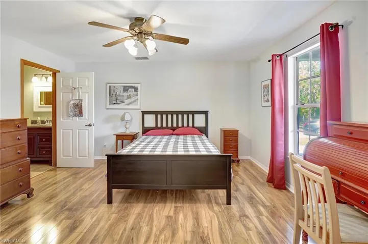 Bedroom featuring light wood finished floors, ceiling fan, and ensuite bathroom