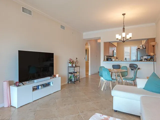 Living room with arched walkways, suspended lighting, crown molding, and light tile patterned floors