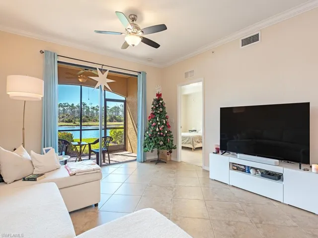 Living room with a ceiling fan, ornamental molding, and light tile patterned floors