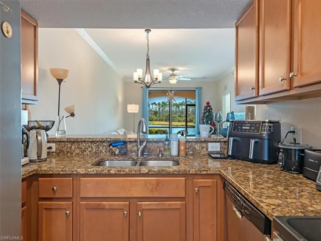 Kitchen with hanging lights, dark stone counters, wood finish cabinets, stainless steel appliances, and a peninsula