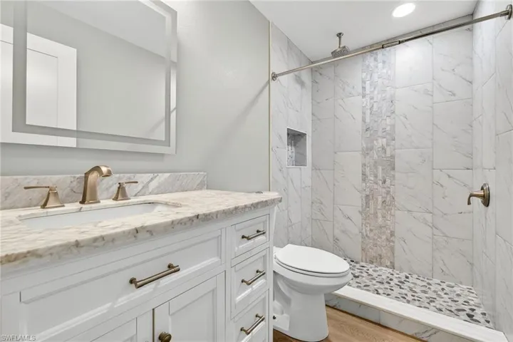 Full bath with vanity, a marble finish shower, and light wood finished floors