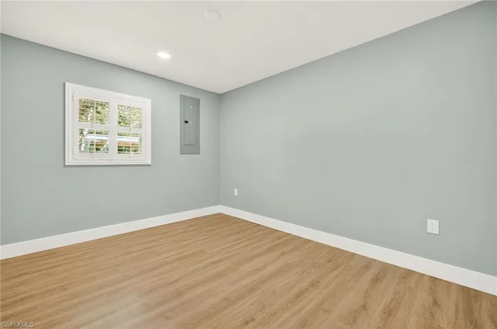 Empty room with wood finished floors, electric panel, and recessed lighting