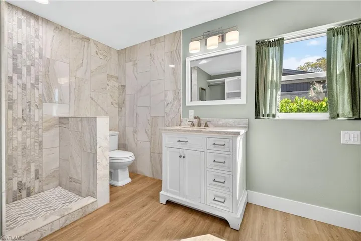 Bathroom with vanity, a shower stall, and light wood-style flooring