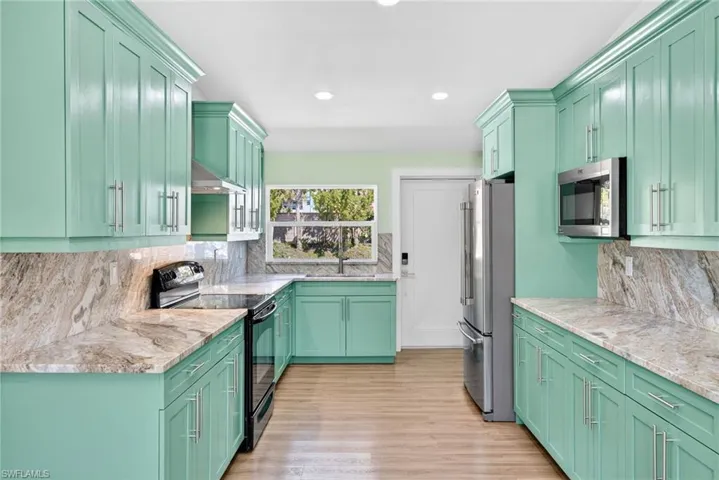 Kitchen with green cabinets, appliances with stainless steel finishes, backsplash, and recessed lighting