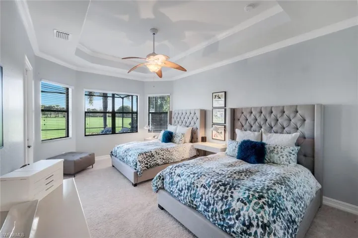 Oversized primary suite on the first floor with lovely windows allowing natural light to pour through and tray ceiling detail with crown molding.