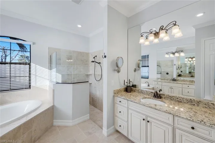 Lovely primary bathroom with two separate vanities, walk-in shower with half privacy wall, built in corner shelfs, and large soaking tub!