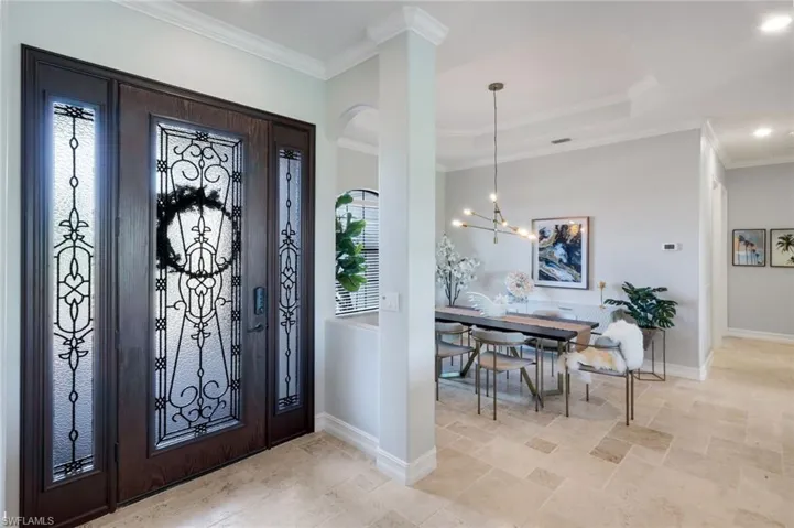 Beautiful entry door with wrought iron detail, open formal dining, crown molding, travertine floors, tray ceilings, not a detail missed!